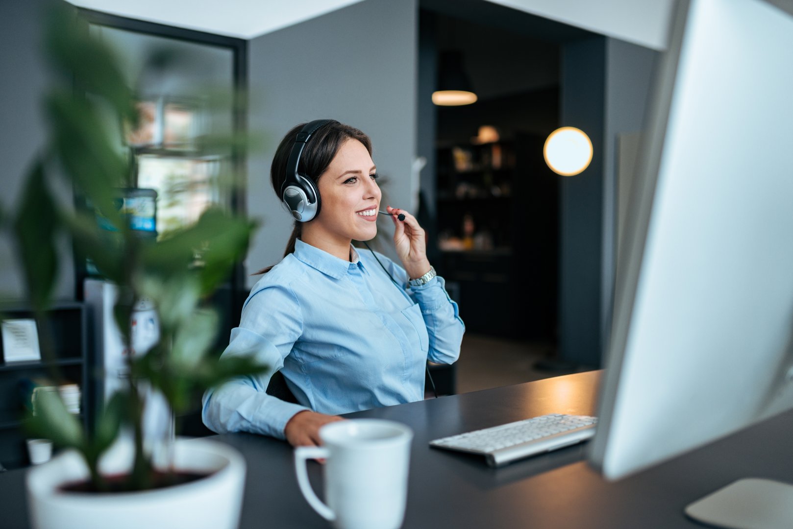 Happy female technical support agent with headset at work im modern